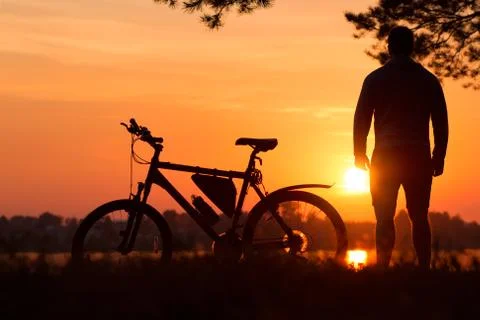 Single bicycle standing on a sunset under trees. Cyclist at sunset Stock Photos