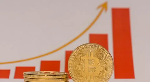 Single bitcoin stands next to a stack of bitcoins with a rising stock market  Stock Photos