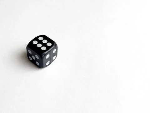 Single black dice with white dots on blank white background Foto stock