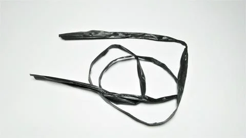 A single black plastic strip coiled on a white background. Stock Photos