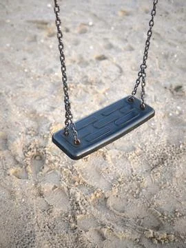 A single black swing on chains at a sand playground Stock Photos
