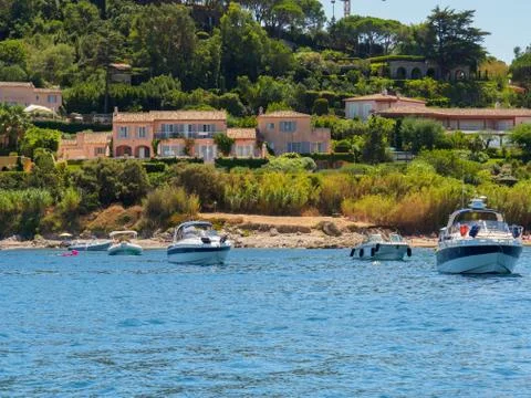 Single boats with multiple villas in the background in Saint-Tropez. Stock Photos