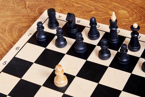 A single brave white pawn attacks the whole black chess army Stock Photos