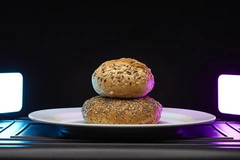 Single bread bun close up on plate with colorful studio lighting Stock Photos