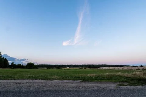 Single bright cloud in the purple sky after sunset over a meadow Foto stock