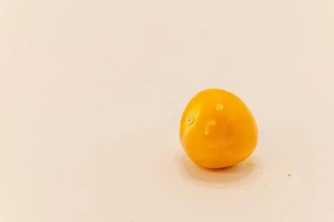 A single, bright orange physalis fruit, also known as a groundcherry, rests o Stock Photos