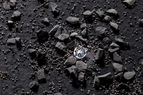 A single brilliantly cut diamond, hidden under dark pebbles and sediment, t.. Stock Illustration