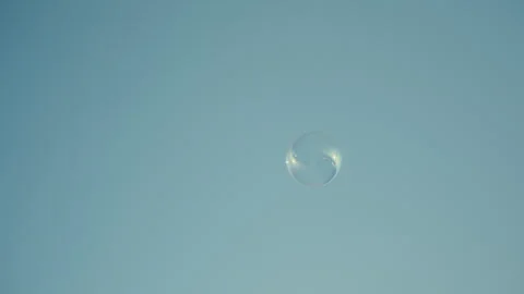 Single Bubble Floating Against Clear Blue Sky with Soft Light Stock Footage 317757866