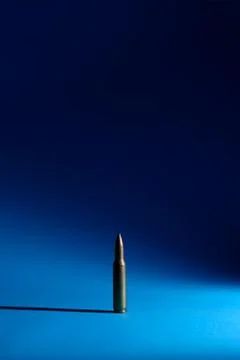 A single bullet standing on a blue ground. Stock Photos