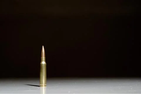 Single bullet on white surface with black background Stock Photos