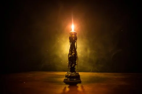 Single burning candle. Light of flame and flowing candle wax, dark background Stock-Fotos