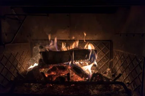 A single burning log inside of a giant wood burning stove Stock Photos