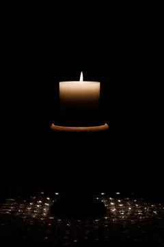 Single candle burning in a dark setting. Stock Photos