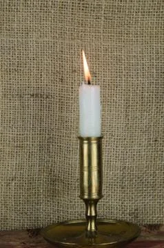 Single candle in candlestick at burlap background Stock Photos