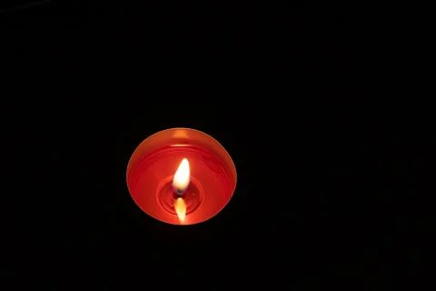 Single candle up close background. Burning red candle on a black background. Stock-Fotos