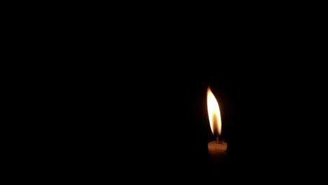 Single candle flame burning against a dark black background with copy space Stock Footage 347572834