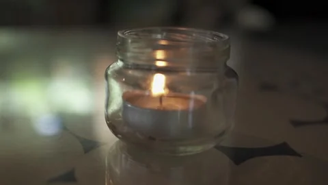 Single Candle Flickering Inside a Glass Jar on a Table Stock Footage 340413887