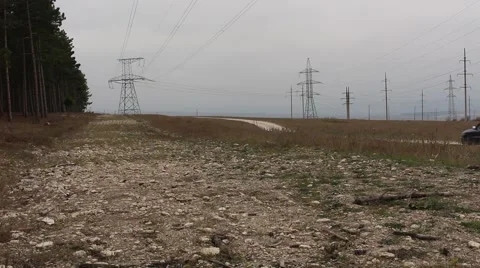 Single car drives by high-voltage lines and forest on rural road in the prairie Stock-Footage 44472036