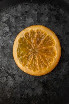 Single Caramelized Orange Slice on a Dark Textured Metallic Background Stock Photos