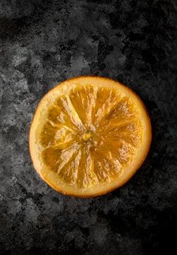 Single Caramelized Orange Slice on a Dark Textured Metallic Background Stock-Fotos