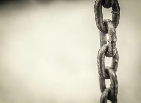 Single chain hanging in a vertical position with a white grunge style backgro Stock Photos