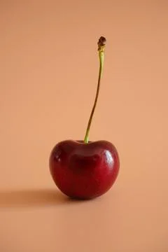 Single cherry on peach background Stock Photos