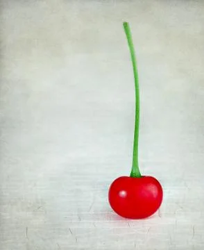 Single cherry on a rustic textured background Foto stock