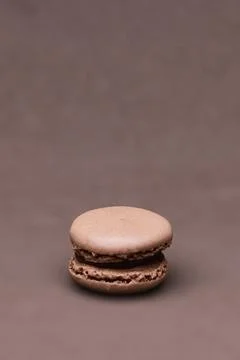 Single chocolate macaron isolated on brown background with copy space for d.. Stock Photos