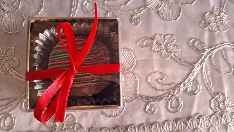 Single chocolate truffle in a box with a red ribbon Stock Photos