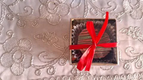 Single chocolate truffle inside a small square box with ribbon Stock Photos