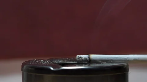 Single cigarette sits in silver ash tray close up isolated smoke slowly dramatic Stock Footage 119078879