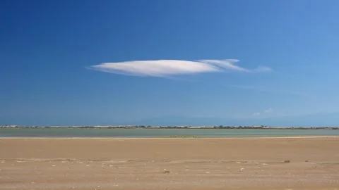 Single cirrus cloud drifts over beach and sea - Cloud Motion and Shoreline Sky Stock Footage 339818755