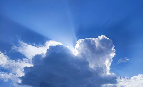 Single cloud in the blue sky with sun rays Stock Photos