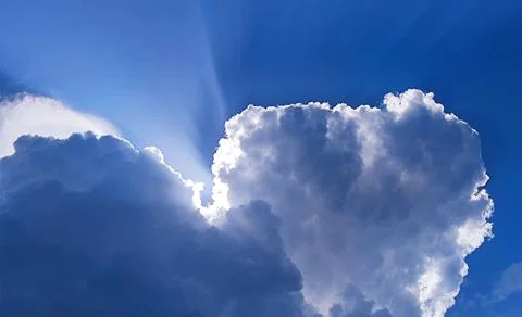 Single cloud in the blue sky with sun rays Stock Photos