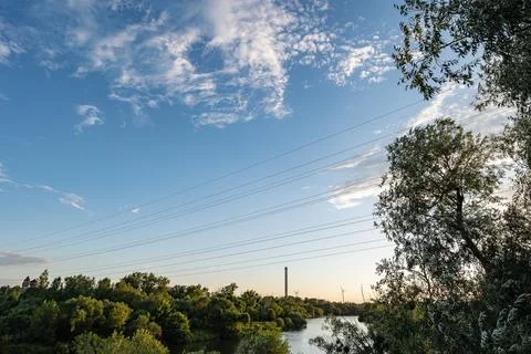 Single clouds at sunset against river in suburban landscape Foto stock