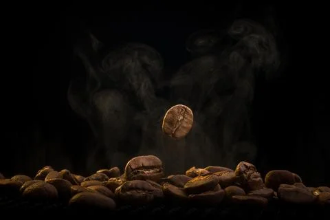 Single Coffee Bean Falling on Heap with Steam Stock Photos