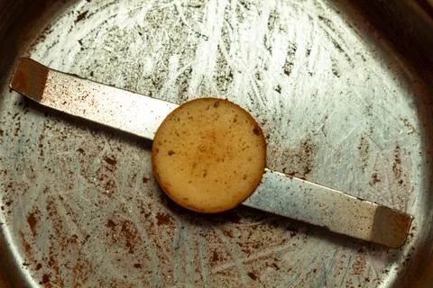 A single coffee bean sample on a metallic surface with kitchen utensil 库存照片