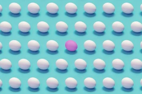 Single colored egg among white eggs solid color background Stock Photos