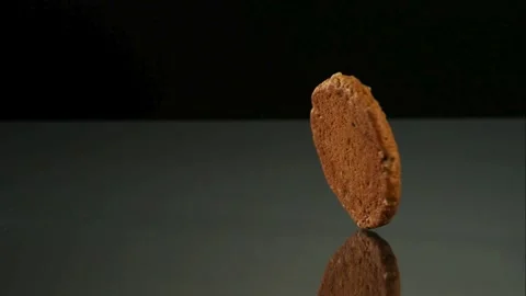 Single cookie spinning on dark reflective surface Stock Footage 327180162