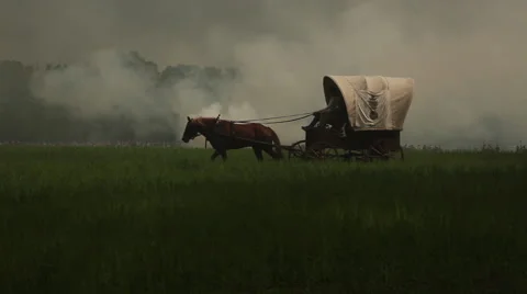 Single covered wagon pulled by horse with smoke and gunfire in distance Stock-Footage 39978791