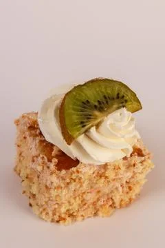 Single cube of light sponge cake topped with a generous swirl of whipped cream Stock Photos