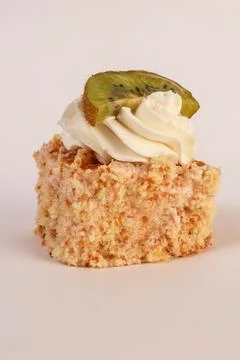 Single cube of light sponge cake topped with a generous swirl of whipped cream Stock Photos