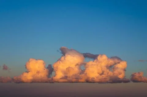 Single cumulus cumulus clouds at sunset sky. Fotos Stock