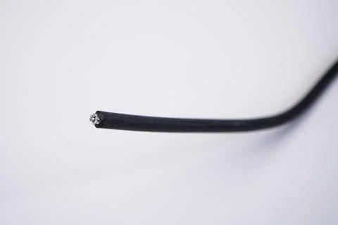 A single cut end of a black electrical wire, exposing the inner metallic co.. Stock Photos