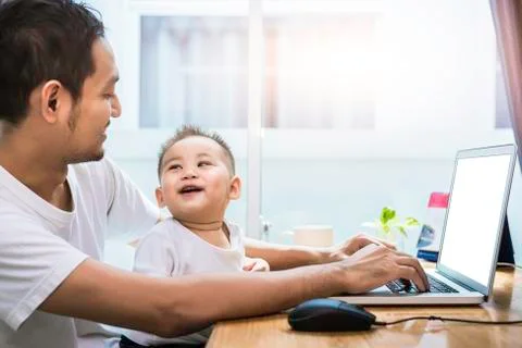 Single dad and son using laptop together happily. Technology and Lifestyles c Photos