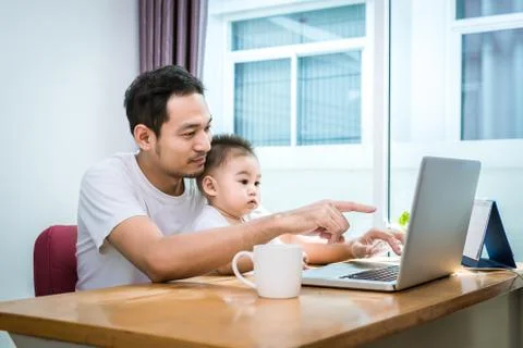 Single dad and son using laptop together happily. Technology and Lifestyles c Photos