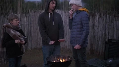 Single dad and two sons. Barbecue fire in backyard, cozy evening Stock Footage 336561058