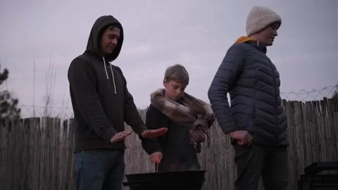 Single dad and two sons. Barbecue fire in backyard, cozy evening Stock Footage 336561087