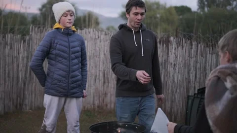 Single dad and two sons. Barbecue fire in backyard, cozy evening Stock Footage 336561088