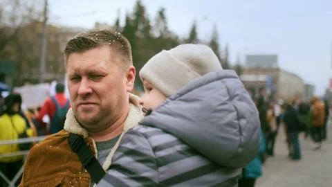 Single dad with kid in arms walking at protest demonstration. Peaceful supporter Stock Footage 166285788